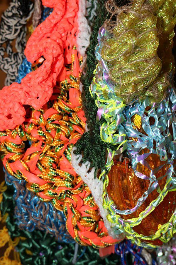 Image Description: Pictured is a small, detailed photograph of Dalbey's work. The materials featured include yarn, rope, ribbon, and found plastic that are woven together into a singular mass.