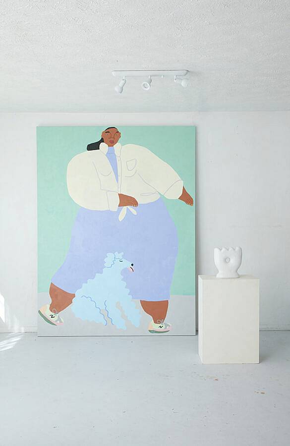 Image Description: This photograph features a large painting of a woman walking in a dress and white jacket with a baby blue poodle near her feet. To the right of the painting is a ceramic sculpture on a white pedestal. The sculpture is shaped loosely like a crown with soft ridges on its to and a circular hole cut through its center.