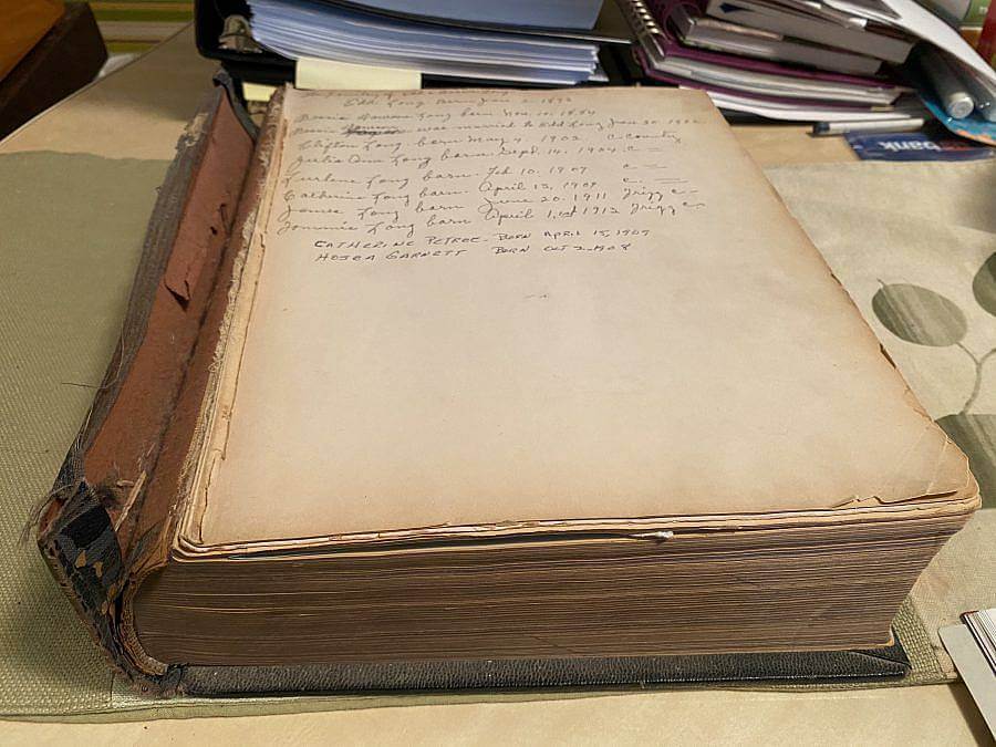 Image Description: This is a photograph of the artist's grandmother's family bible. The front cover has fallen off and the spine is very worn. There appears to be a list of names and dates at the top of the first page.