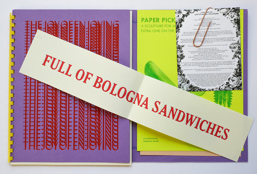 Excerpt from the Joy of Enjoying book. The left page has "They Joy of Enjoying" overlayed over itself in a straight pattern all the way down the page. An insert on top reads "Full of Bologna Sandwiches" in all caps. The page of the right reads "Paper Picks" there is a recipe card paperclipped on top of it.