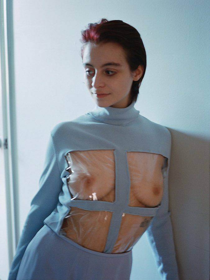 Image desceription: Photograph of artist and designer Martina Cox. She is a white woman with short dark red slicked back hair. She wears a baby blue dress with a window pane on the front. Her chest and torso are on full display.