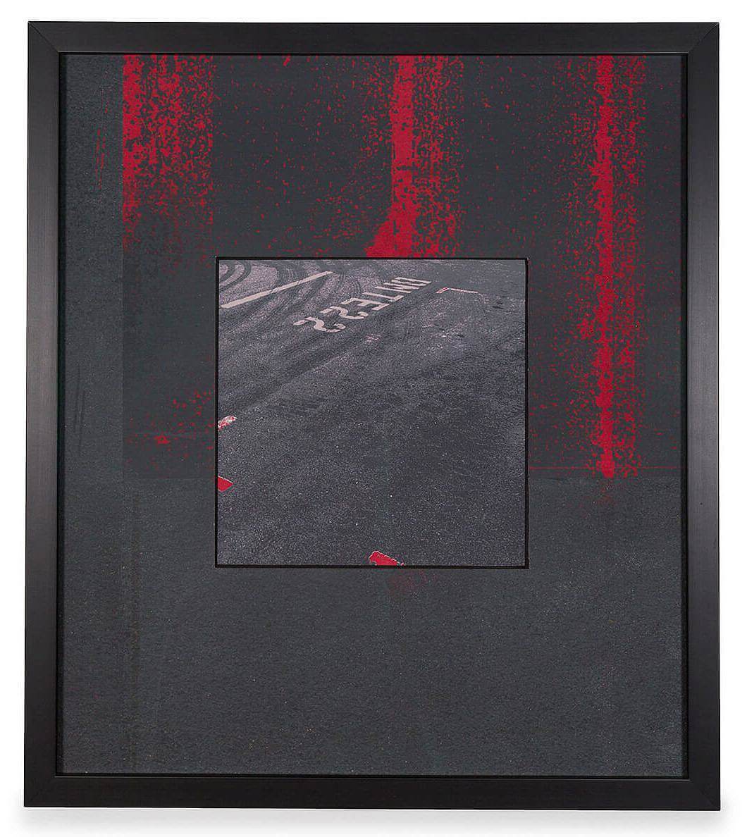 Image Description: There is a square image in the center of the piece that depicts a birds-eye view of an asphalt parking lot or street. The image is surrounded by a thick black border with bright red vertical streaks coming down from the top. 