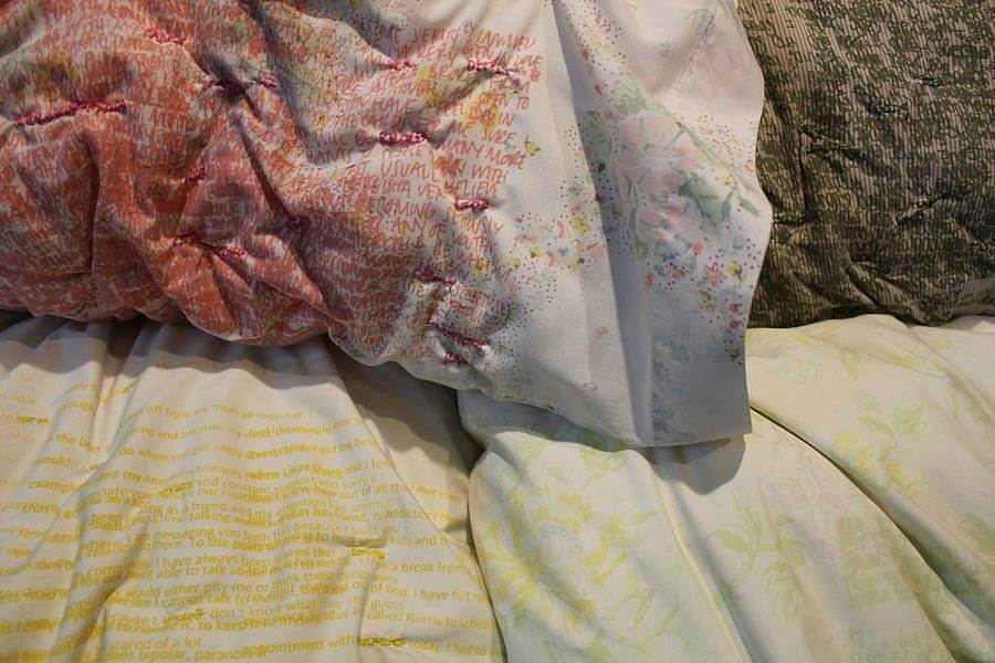 Image description: Four pillow cases are displayed. The one most centered has orange layered writing all over it To its left a soft brown has green writing layered on it. Below the white pillowcase is one with mustard yellow writing. The pillowcase beneath that has a soft green and lilac floral pattern.