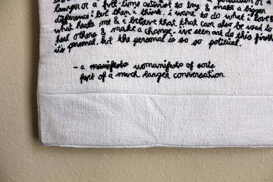 Image description: black text is embroidered on a fabric in cursive. Certain parts can be made out, like " The personal is so so political," it is titled " - a manifest womanifesto of sort part of a much longer conversation" 