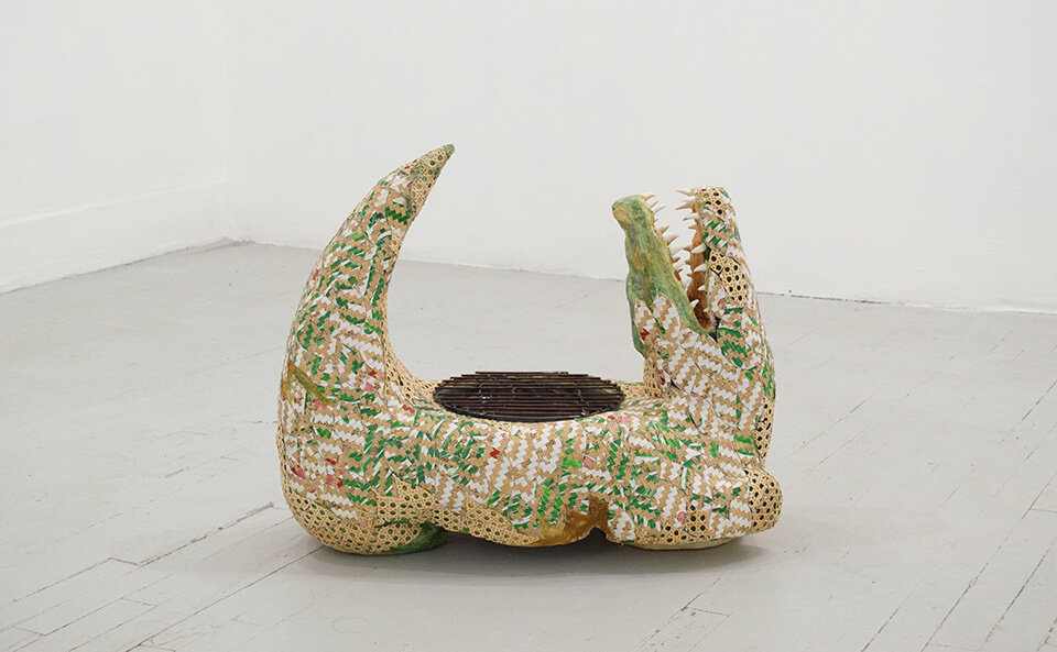 Image description: This is a photograph of a sculpture titled Amazonas 2000 by Sacha Ingber. This sculpture is displayed on the floor, it is shaped like an alligator with a circular grill on its back.