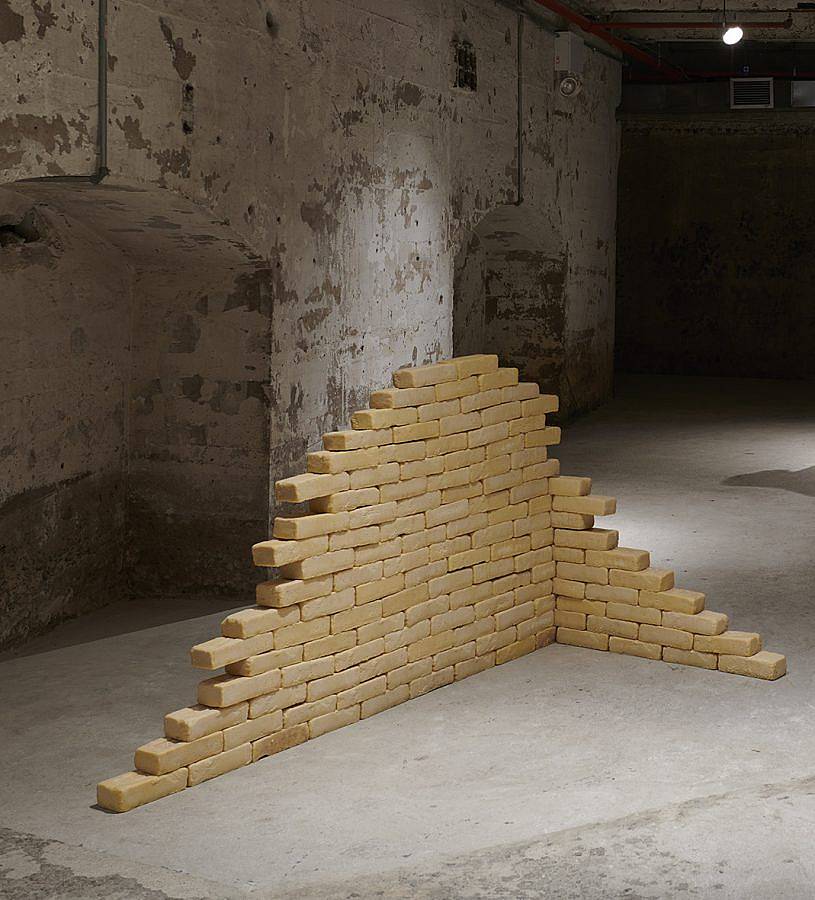 Image Description: There are a large collection of bricks cast in tan cocoa butter. They are arranged in a corner formation with one wall higher than the other.