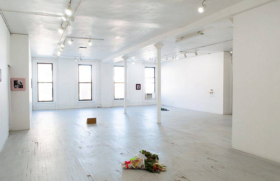 Image Description: This is an installation shot of the gallery. The photograph is facing the windows of the gallery. There are several pieces hung on the walls and sitting on the floor.